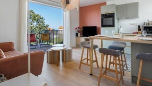 A modern apartment with a dining area, kitchen, and a balcony with outdoor furniture. - Gîtes de France® - La Villa Pomponette (CRIEL SUR MER)