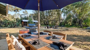 An outdoor dining area with a large umbrella, wooden tables, and chairs. - NEW Hot Tub-Fire Pit-Arcade Game-BBQ (Mariposa)