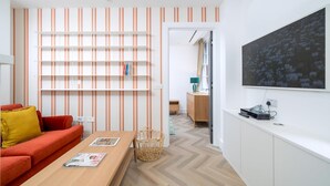 Ein modernes Wohnzimmer mit Sofa, Couchtisch, Bücherregal und einem großen Gemälde an der Wand.