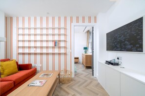 Ein modernes Wohnzimmer mit Sofa, Couchtisch, Bücherregal und einem großen Gemälde an der Wand.
