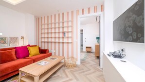 Ein modernes Wohnzimmer mit einer Couch, einem Holztisch, einem Bücherregal und einem Fernseher.
