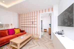 Ein modernes Wohnzimmer mit einer Couch, einem Holztisch, einem Bücherregal und einem Fernseher.