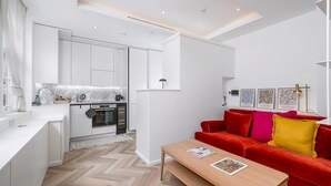 Eine moderne Wohnung mit Küche, Essbereich und einem roten Sofa mit Kissen.