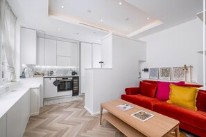 Eine moderne Wohnung mit Küche, Essbereich und einem roten Sofa mit Kissen.