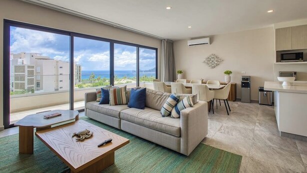 Uma sala de estar moderna com sofá, mesa de centro e área de jantar.