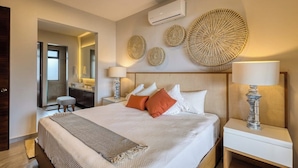 Quarto de hotel com cama, luminárias de cabeceira, espelho e decoração na parede.