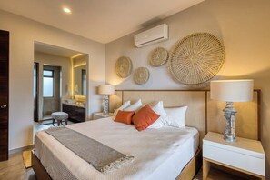 A hotel room with a bed, bedside lamps, a mirror, and decorative wall art. - Peaceful Coastal Stay With Pool, Balcony & Fitness Center (Cabo San Lucas)