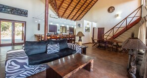 A spacious living area with a sofa, coffee table, dining table, and staircase.