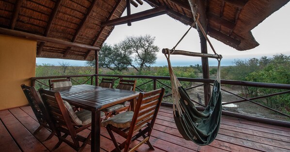 Eine Holzterrasse mit Tisch und Stühlen, einer Hängematte und Blick auf die Landschaft.