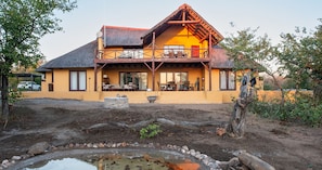 A two-story building with a balcony, outdoor seating, and a small pond.