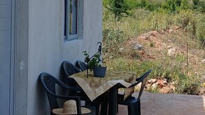 Un petit bâtiment avec une table et des chaises à l’extérieur, une fenêtre et une vue sur un paysage verdoyant.