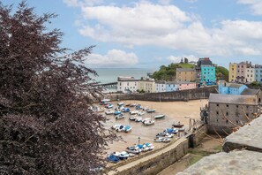 A coastal town with a sandy beach, a row of colorful buildings, and a stone wall. - Tenby Harbour View - Heart of Tenby, Sea Views (Tenby)