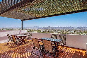 Eine Terrasse mit Blick auf Stadt und Berge, mit Tisch und Stühlen.
