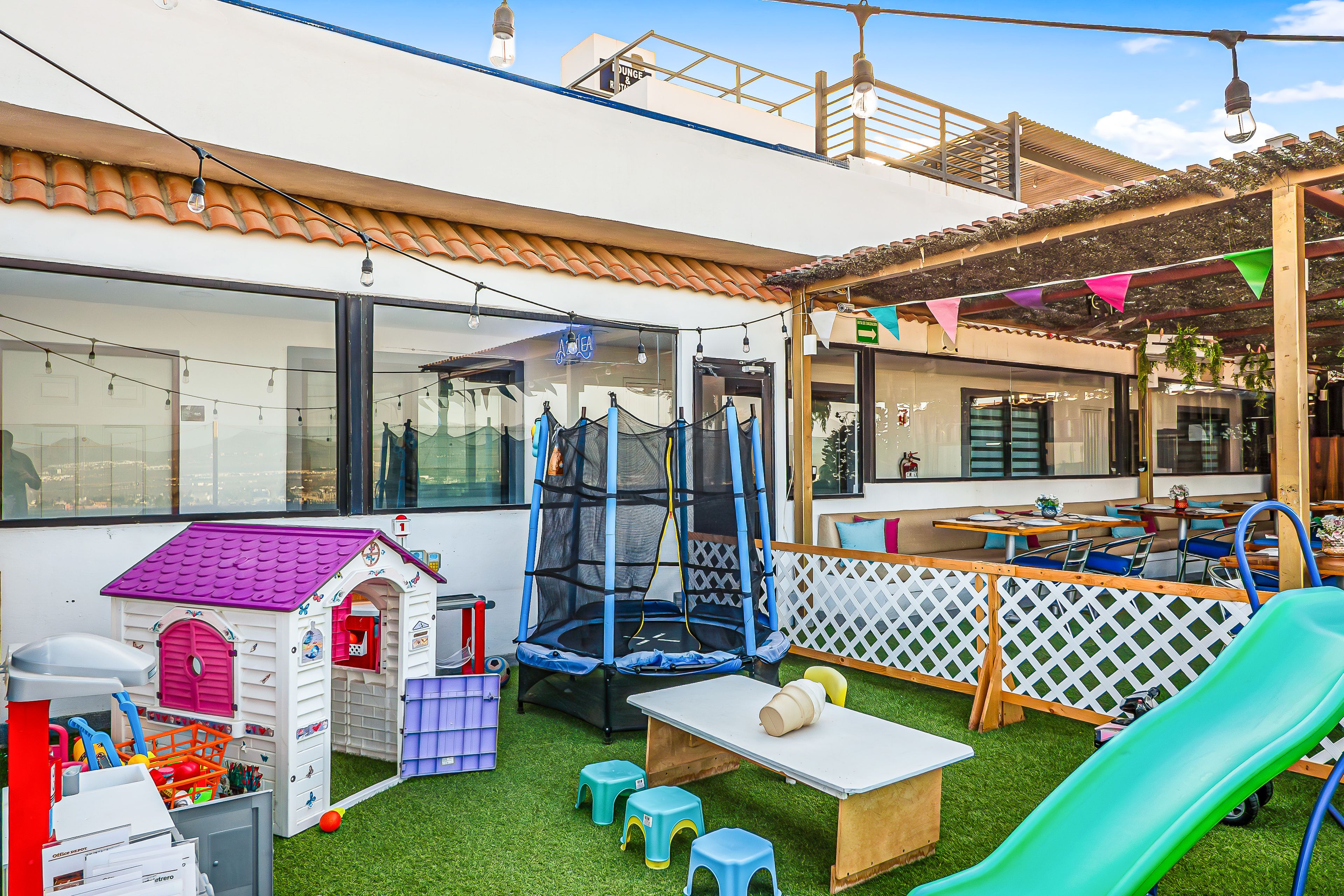 A children's play area with a trampoline, small house, and slide.