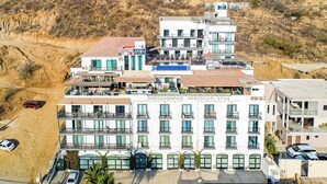 A multi-story hotel with balconies, a rooftop terrace, and a view of a hilly landscape. - Cerro Colorado Studio Condo in Cabo San Lucas (Cabo San Lucas)