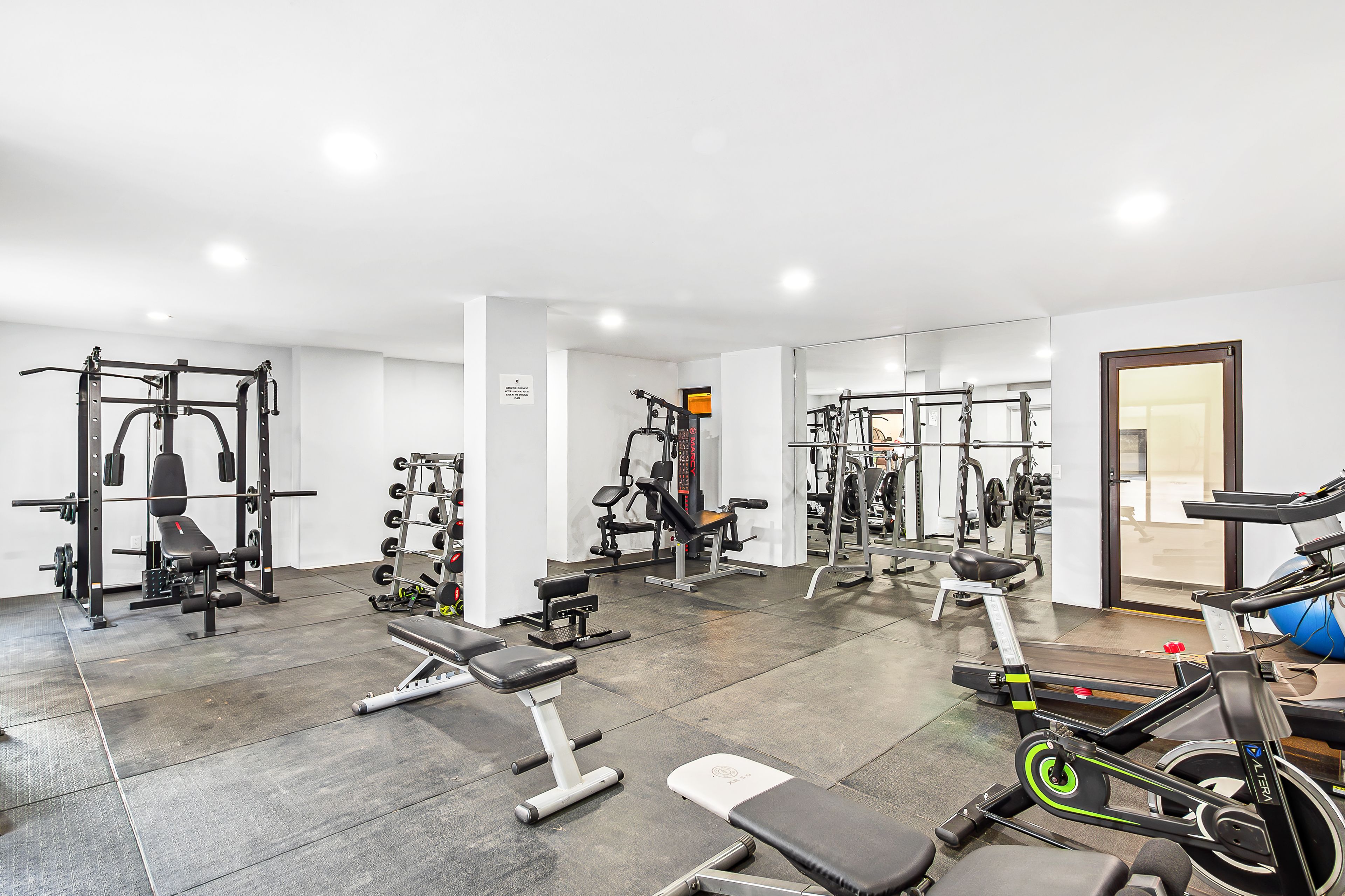 A gym with various exercise equipment, including weight machines, benches, and cardio machines.