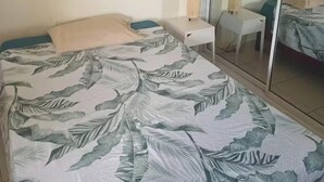A bedroom with a bed, a bedside table, a nightstand, a mirror, and a painting on the wall.