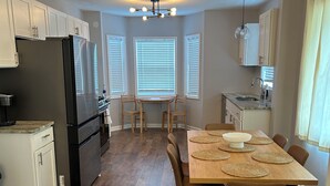 A modern kitchen with a refrigerator, dining table, chairs, and a ceiling light fixture. - Awesome 6-bedroom house with AC in vibrant Detroit (Detroit)