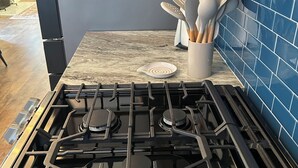 A kitchen with a gas stove, a white utensil holder, and blue tiled backsplash. - Awesome 6-bedroom house with AC in vibrant Detroit (Detroit)