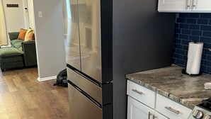 A kitchen with a stainless steel refrigerator, white cabinets, a marble countertop, and a wooden floor. - Awesome 6-bedroom house with AC in vibrant Detroit (Detroit)