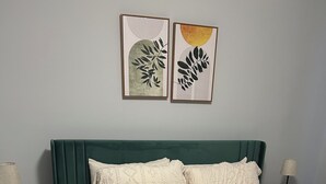 A neatly made bed with a green headboard, two pillows, a folded towel, and two framed artworks on the wall. - Awesome 6-bedroom house with AC in vibrant Detroit (Detroit)