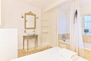 A bathroom with a sink, mirror, and bathtub. - Maison rare avec terrasse et 2 chambres - Marais (Paris)