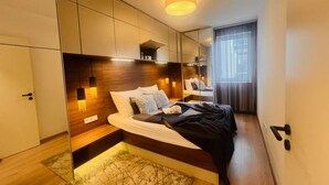 Moderni hotellihuone, jossa on suuri sänky, sisäänrakennettu vaatekaappi ja ikkunasta avautuva n äkymä kaupunkiin.