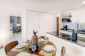 Une cuisine moderne avec des meubles blancs, un four à micro-ondes et une machine à café.