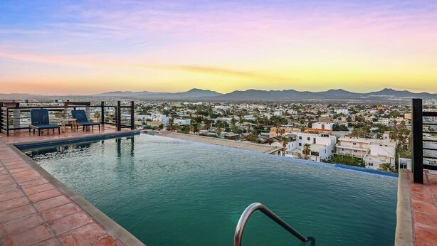A rooftop infinity pool with a city view, a railing, and a few lounge chairs. - Cerro Colorado Condo Condo in Cabo San Lucas (Cabo San Lucas)
