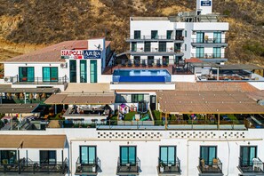 A multi-story building with a pool, outdoor seating, and a sign for 'NAPOLI PIZZA & PASTA'. - Cerro Colorado Condo Condo in Cabo San Lucas (Cabo San Lucas)