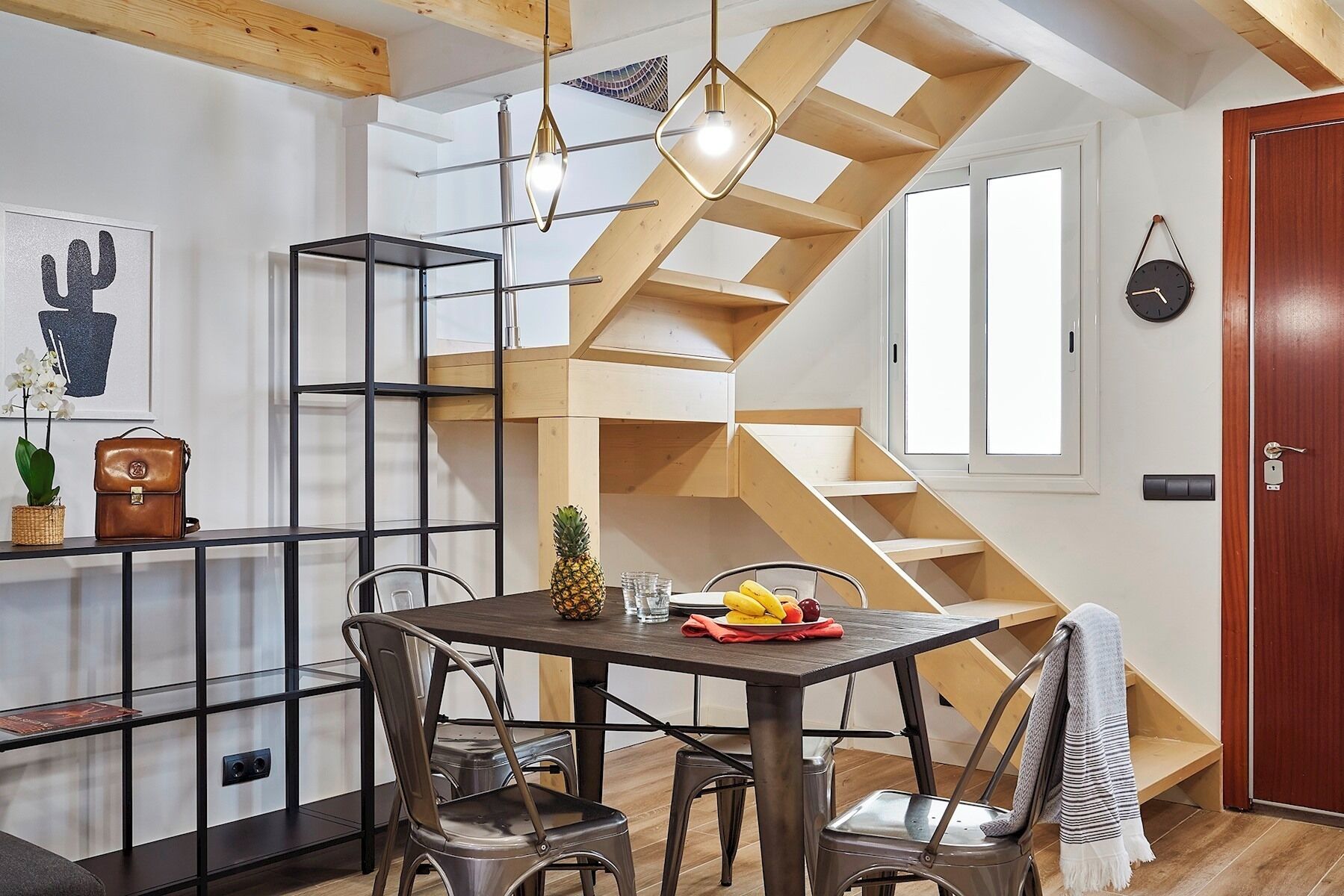 A modern kitchen with a central island, wooden beams, and a built-in staircase.