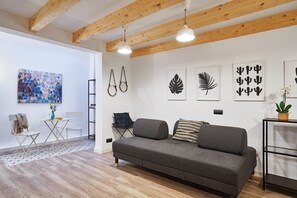 A modern living room with a grey sofa, wooden beams, and artwork on the walls. - Planell · BOLSA 2H - Two Bedroom Apartment, Sleeps 4 (Barcelona)