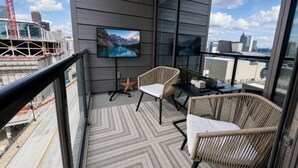 A balcony with a TV, wicker chairs, and a star decoration. - Prime Atlanta Location 2026 Flat close to everything! (Atlanta)