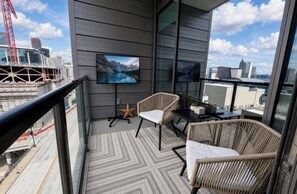 Ein Balkon mit Fernseher, Korbstühlen und einer Sternen-Dekoration.