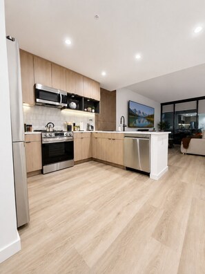 Eine moderne Küche mit Holzschränken, Edelstahlgeräten und einer großen Kochinsel.