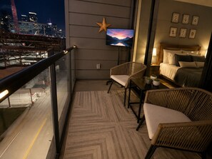 Ein Balkon mit Stadtblick, einem Fernseher, Korbstühlen, einem Bett und einer Stern-Dekoration.