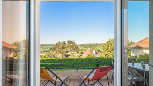 Ein Balkon mit Blick auf eine grüne Landschaft und Häuser.