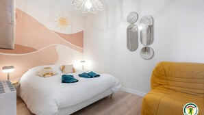 Ein Schlafzimmer mit Bett, Nachttischlampen, einem Wandspiegel und einem Sofa.