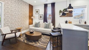 Een moderne woonkamer met een bank, een salontafel en een keukenhoek met een barkruk.