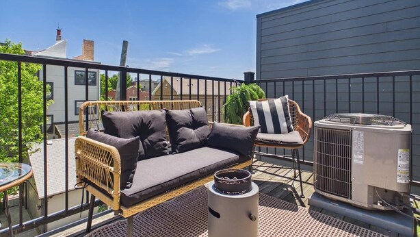 Een balkon met een bank, een stoel en een airconditioning.