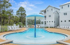 A swimming pool with a water fountain, surrounded by lounge chairs and a building with balconies. - Dune & Pine - 4 Ensuite Bedrooms -3 King Beds, Community Pool, Bikes + Beach (Santa Rosa Beach)