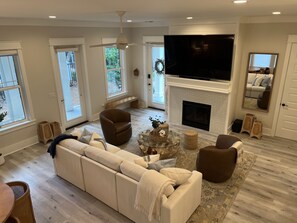 A living room with a sofa, armchairs, a fireplace, a TV, and large windows. - Dune & Pine - 4 Ensuite Bedrooms -3 King Beds, Community Pool, Bikes + Beach (Santa Rosa Beach)