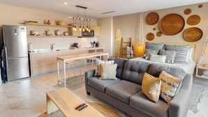 Uma sala de estar moderna com sofá, mesa de jantar e área de cozinha.