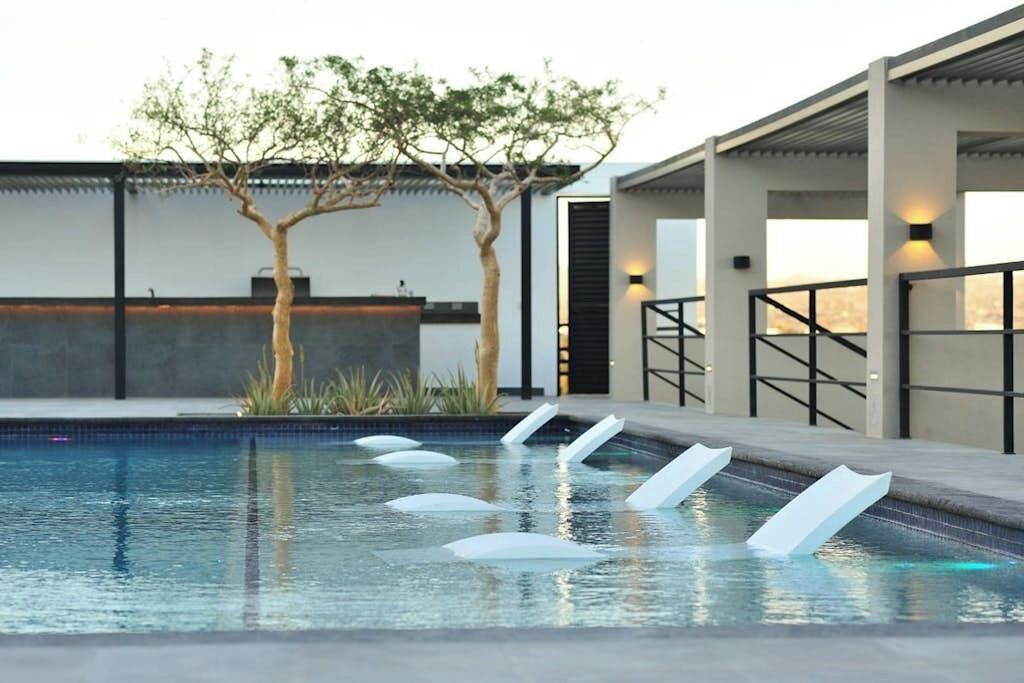 A swimming pool with a modern design, including a unique water feature and a contemporary outdoor seating area.