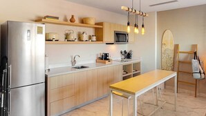 Uma cozinha moderna com geladeira de aço inoxidável, armários de madeira, micro-ondas e uma mesa de jantar de madeira.