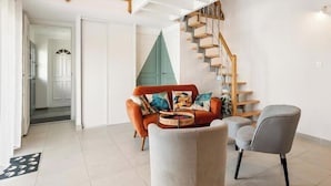 A living room with a sofa, armchair, and a staircase.