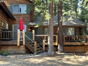 Eine Blockhütte mit einer Holzterrasse, einer überdachten Außenlounge und einer Treppe zum Eingang.