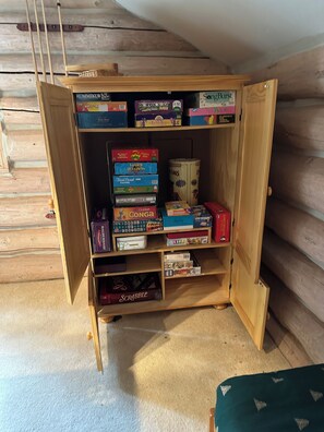 A wooden shelf with various board games and a roll of toilet paper. - Log Cabin Bliss ~ Game Room ~ Pets ~ WiFi (Carnelian Bay)