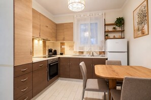 Eine moderne Küche mit Holzausstattung, Backofen, Esstisch mit Stühlen und Kühlschrank.