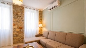 Een woonkamer met een stenen muur, een beige bank, een houten salontafel en een lamp.